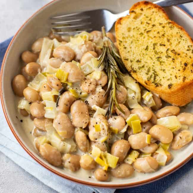 A bowl of creamy butter beans, served with garlic bread.