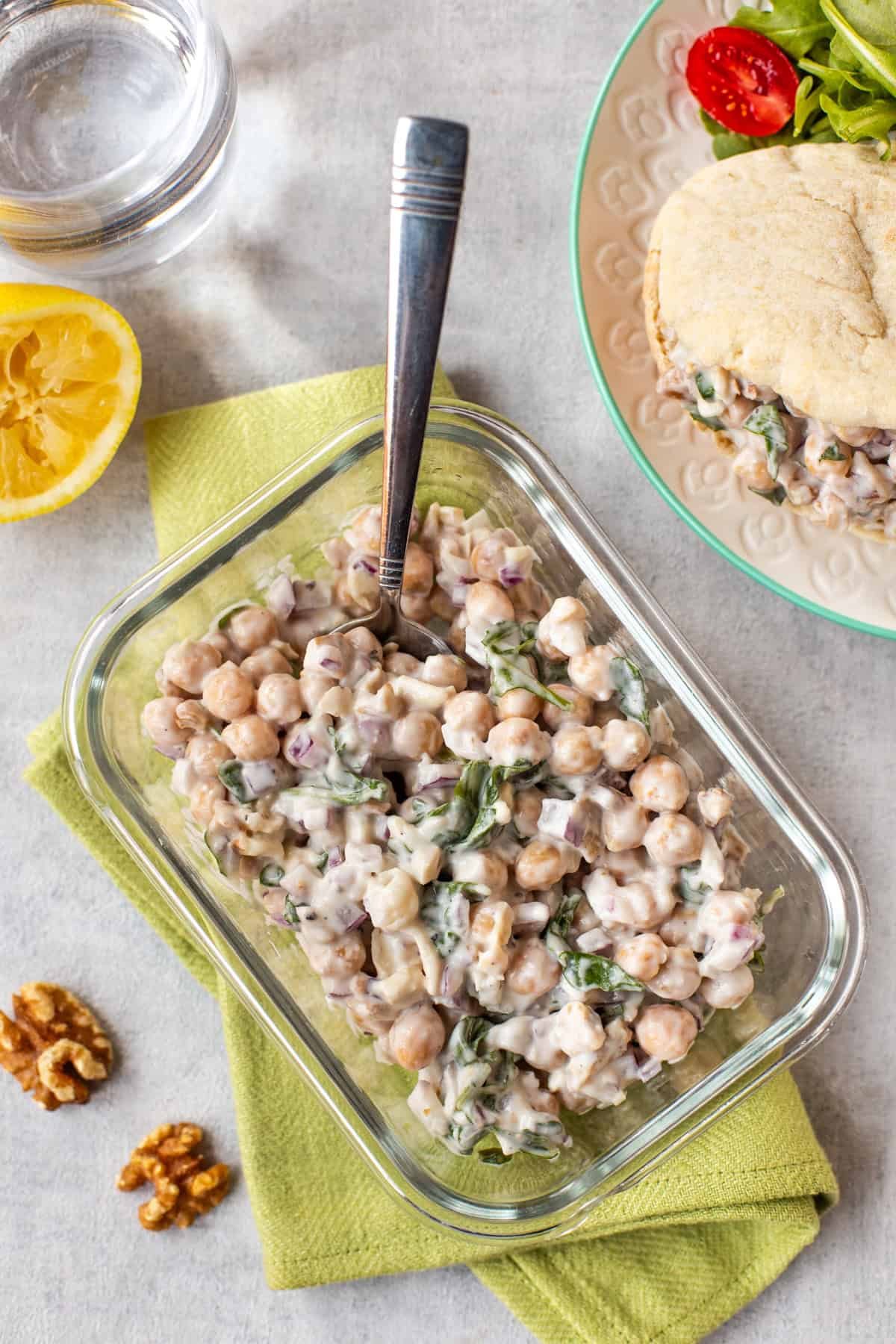 Overhead shot of lemony chickpea salad in a tub with goat cheese and walnuts.