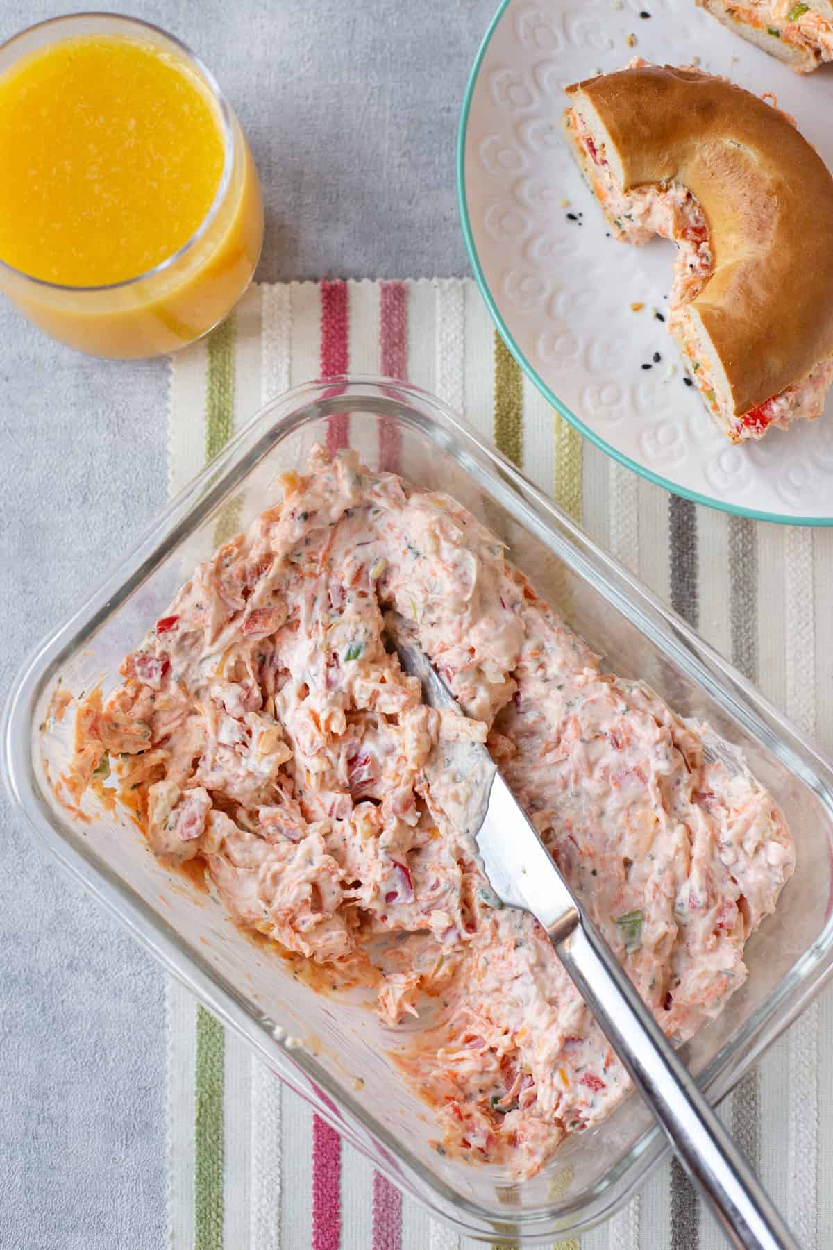 Overhead shot of a tub of vegetable cream cheese with a knife.