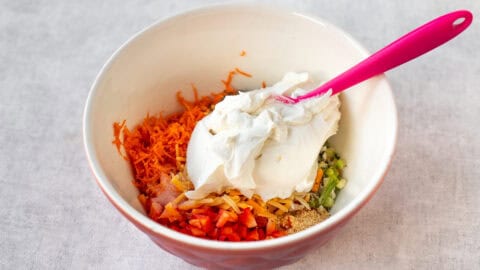 A mixing bowl with ingredients for vegetable cream cheese.