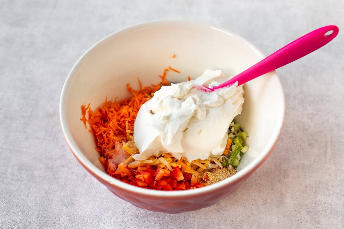 A mixing bowl with ingredients for vegetable cream cheese.