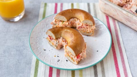 A halved bagel stuffed with vegetable cream cheese on a plate.