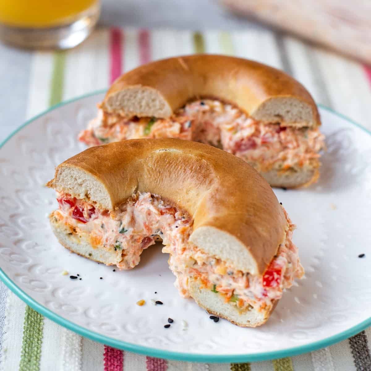 A halved bagel stuffed with vegetable cream cheese on a plate.