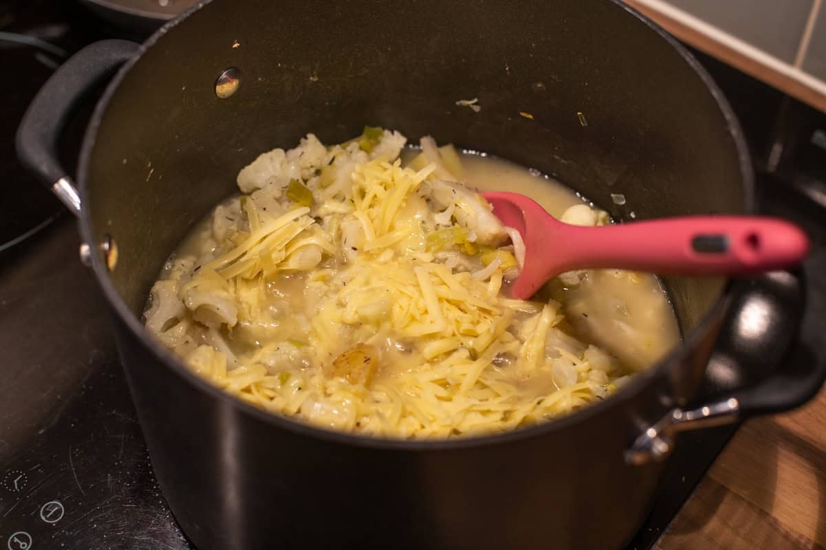 Unblended cauliflower soup with cheese in a large saucepan.