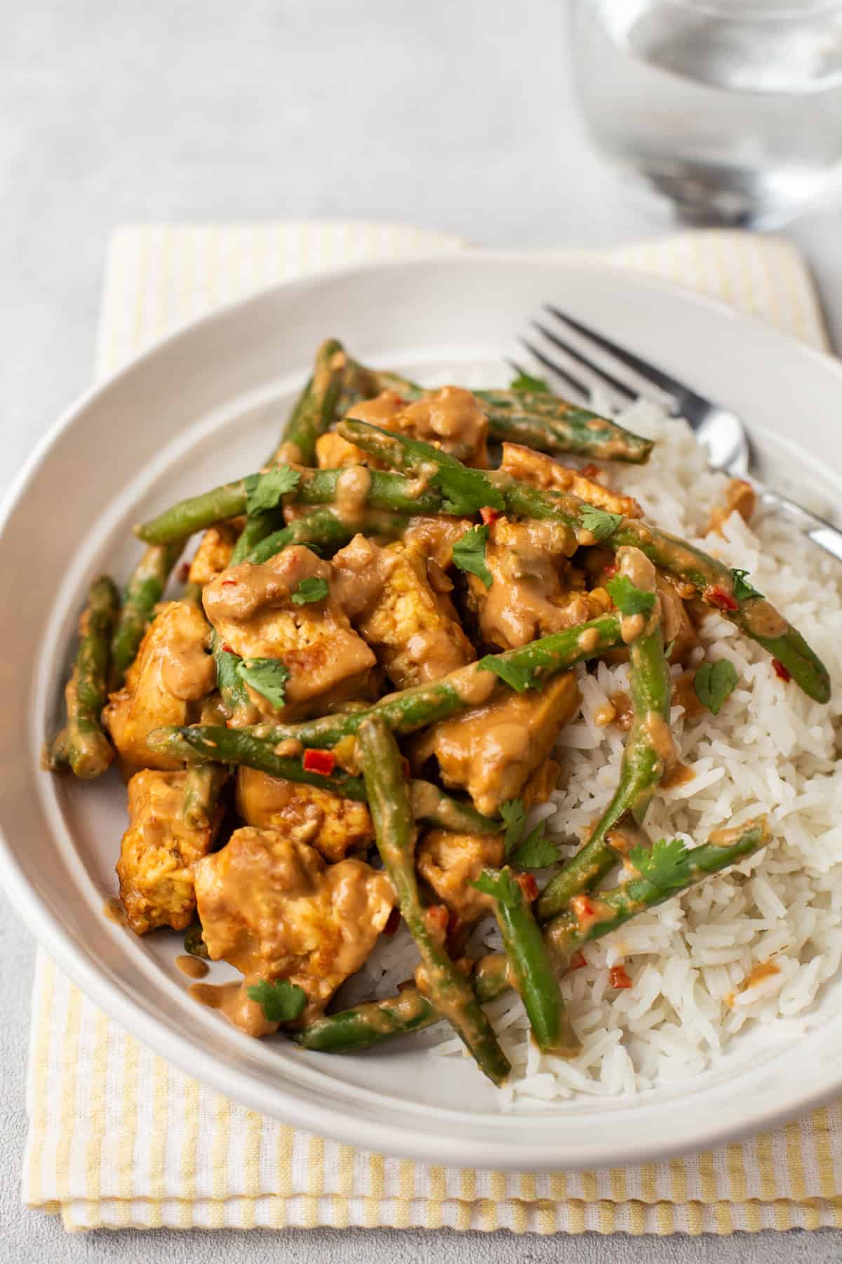 Peanut butter tofu and rice with green beans in a bowl.