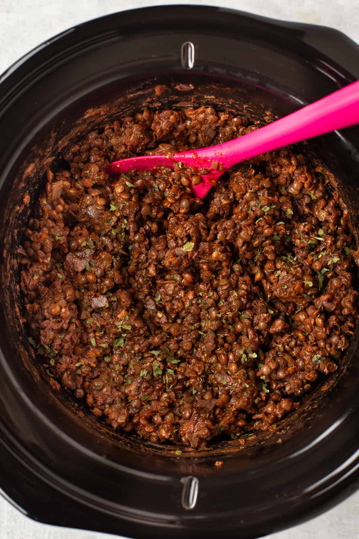 Overhead shot of a rich lentil bolognese in a slow cooker.