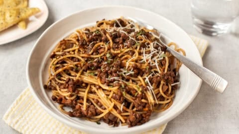 A portion of slow cooker lentil bolognese with spaghetti in a bowl.