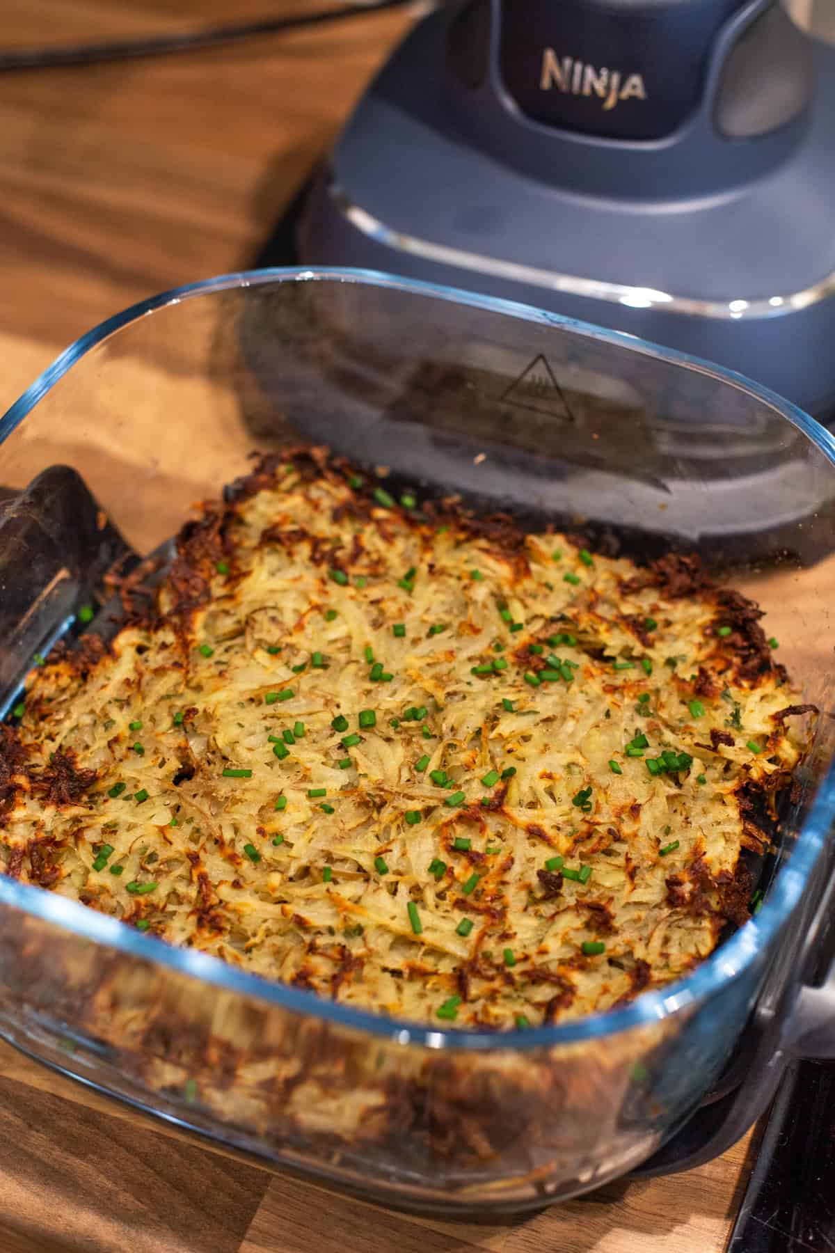 Crispy homemade hash browns in an air fryer topped with chives.