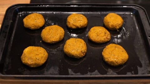 Uncooked homemade falafel on a baking tray.