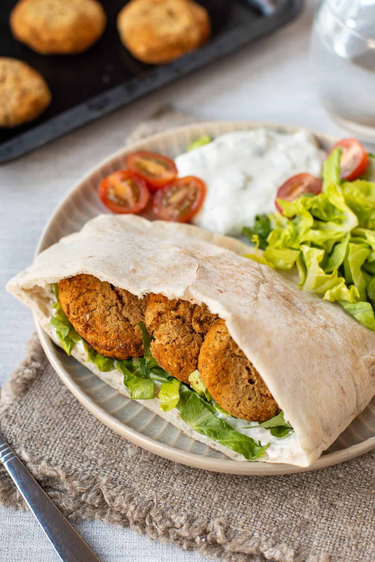 Homemade baked falafel stuffed into pitta bread with salad and tzatziki.