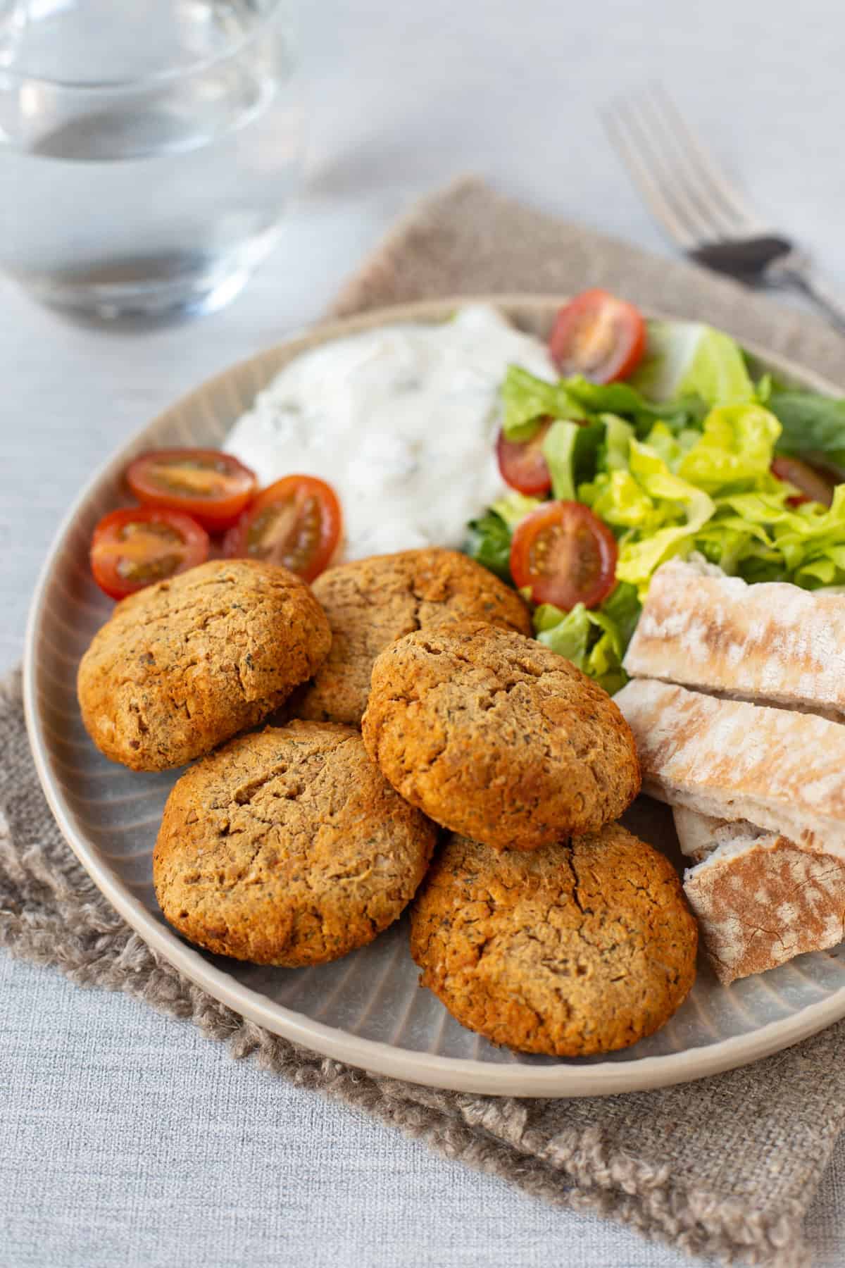 Homemade baked falafel on a plate with pitta bread, salad and tzatziki.