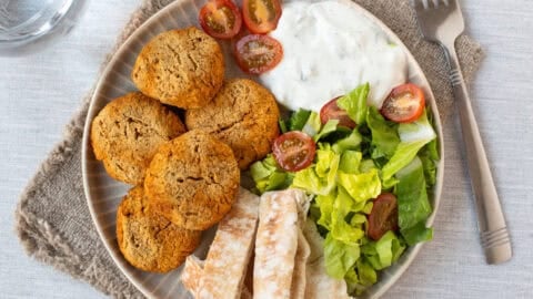 Overhead shot of falafel on a plate with pitta bread, salad and tzatziki.