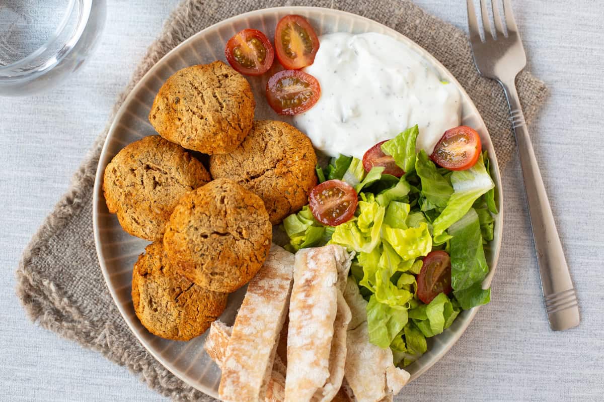 Overhead shot of falafel on a plate with pitta bread, salad and tzatziki.