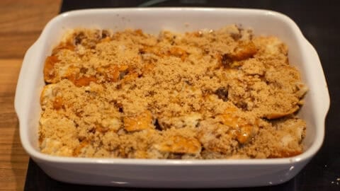 An uncooked bread and butter pudding topped with brown sugar.