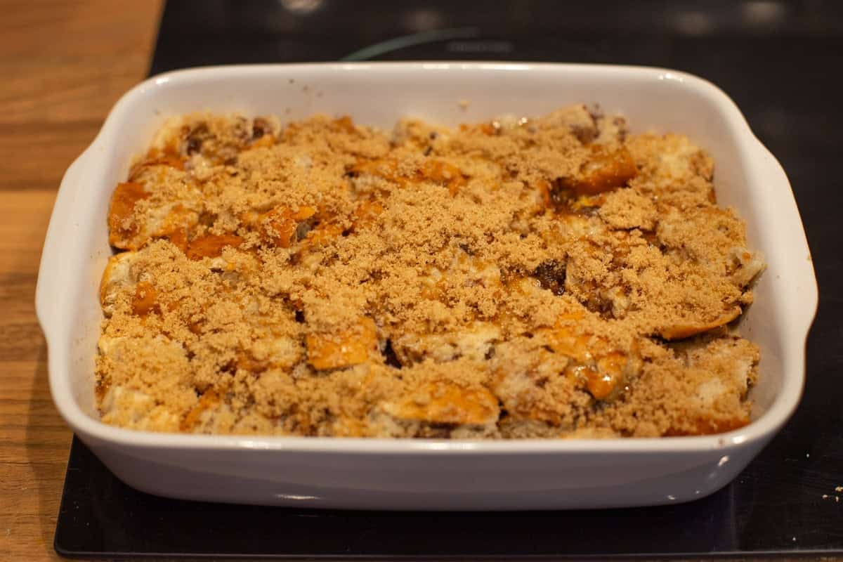 An uncooked bread and butter pudding topped with brown sugar.