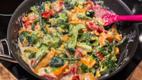 Vegetables in a creamy sauce in a frying pan.