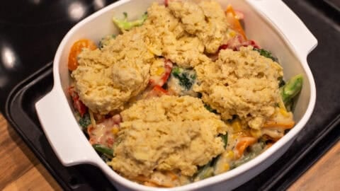 Uncooked vegetable cobbler topped with cheesy scone mixture.