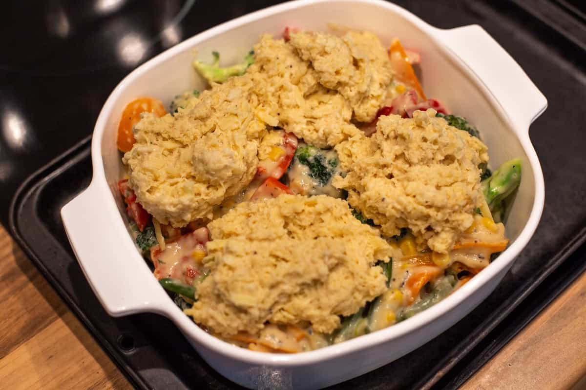 Uncooked vegetable cobbler topped with cheesy scone mixture.