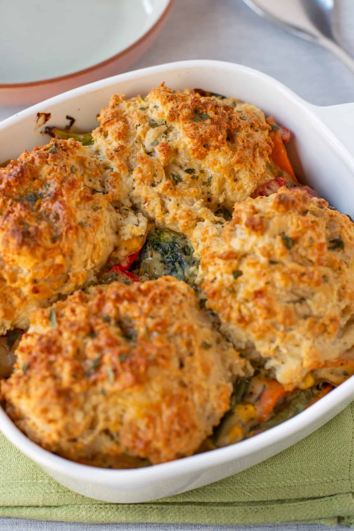 Vegetable cobbler topped with crispy cheese scones in a baking dish.