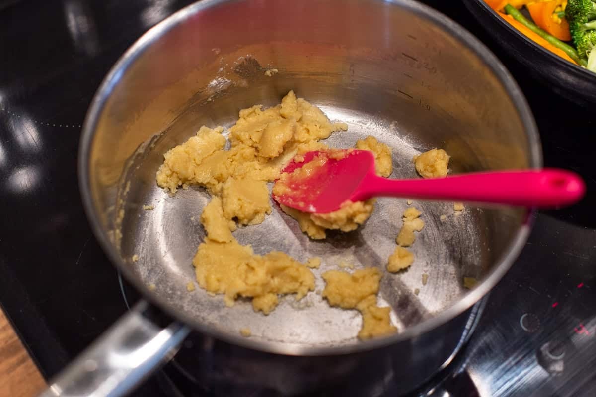 A roux made from butter and flour cooking in a saucepan.