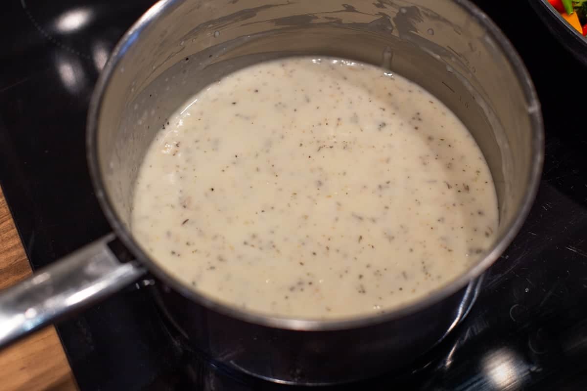 Seasoned white sauce in a saucepan.