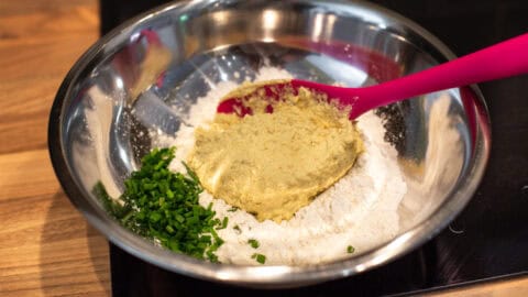 Flour, chives and hummus in a mixing bowl.