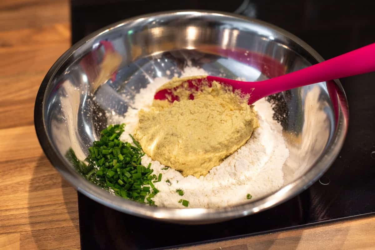 Flour, chives and hummus in a mixing bowl.