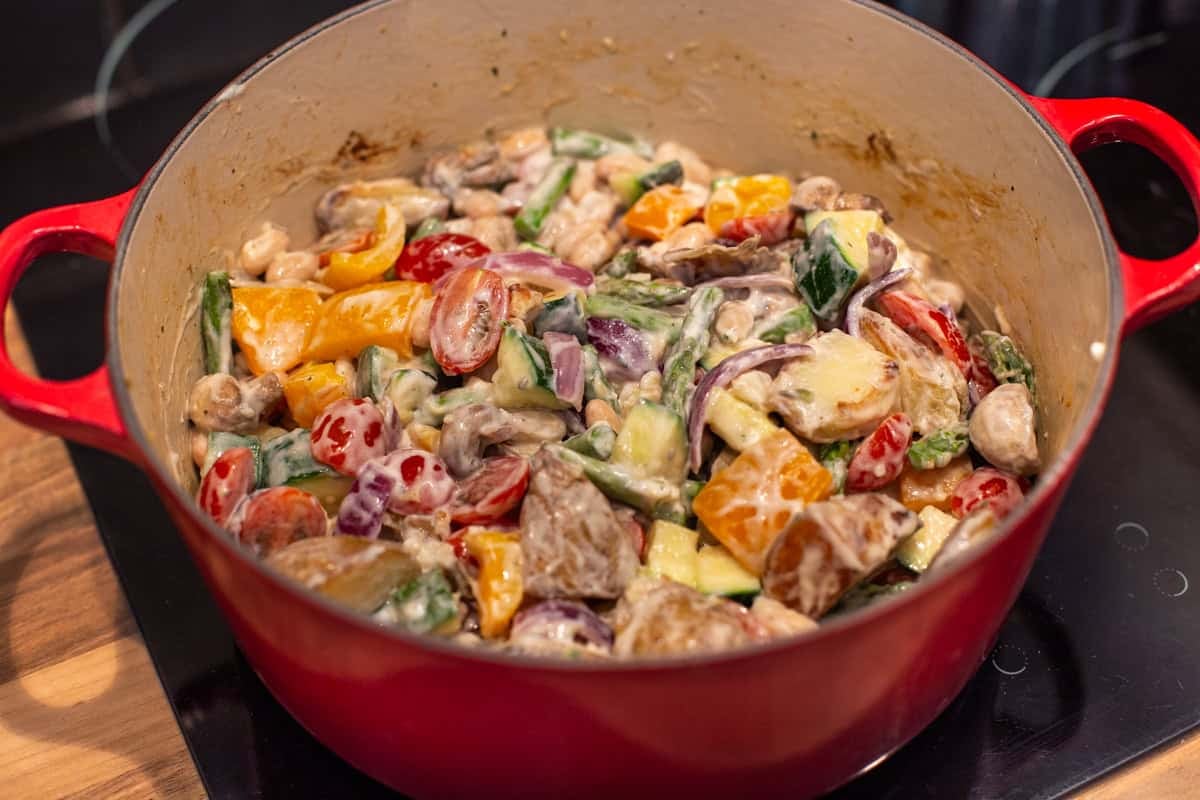 Colourful vegetables in a cream cheese sauce in a big pot.