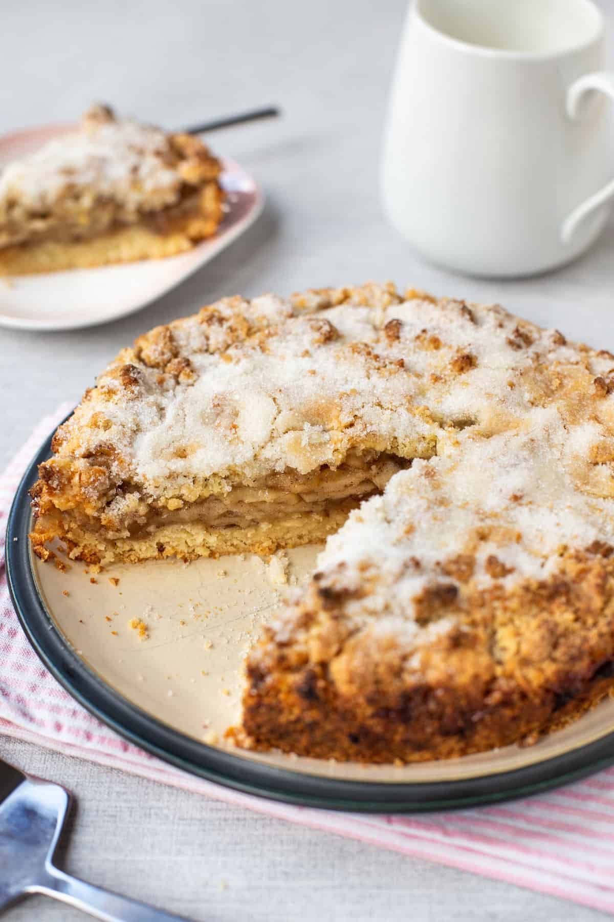 An easy apple crumble cake on a plate topped with sugar.
