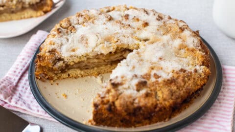 An easy apple crumble cake on a plate with a slice removed.