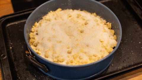Uncooked apple crumble cake in a springform cake tin.