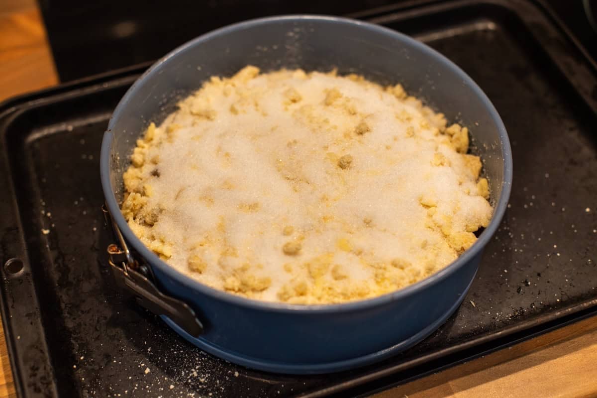 Uncooked apple crumble cake in a springform cake tin.