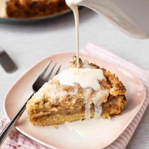 Cream being poured onto a slice of easy apple crumble cake.