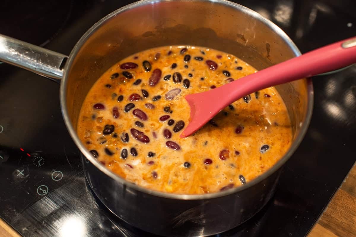 Kidney beans and coconut milk with spices in a saucepan.