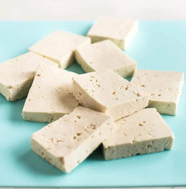 Slices of tofu on a blue chopping board.