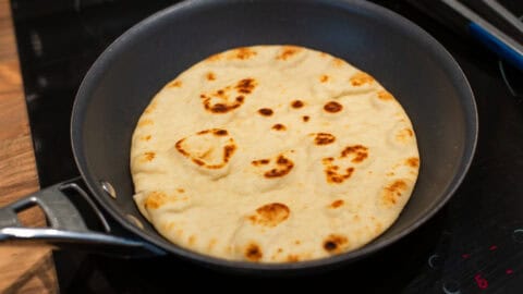 A flatbread cooking in a frying pan.