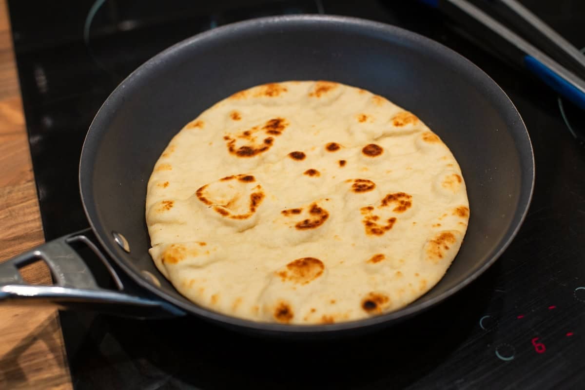A flatbread cooking in a frying pan.