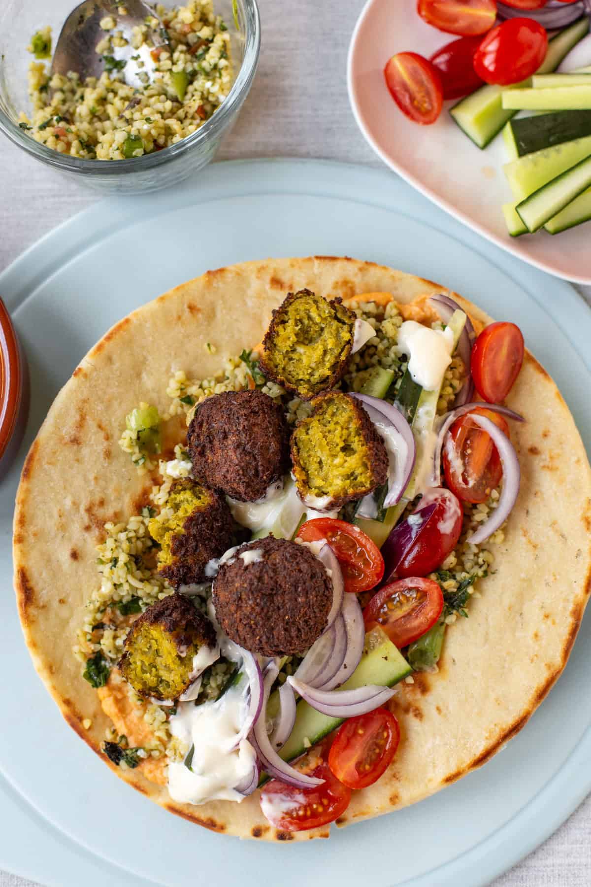 Overhead shot of a falafel and tabbouleh wrap with hummus and vegetables.