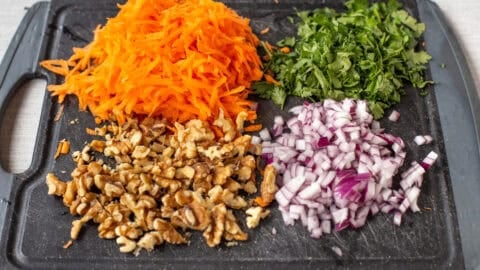 Chopped vegetables and nuts on a cutting board.