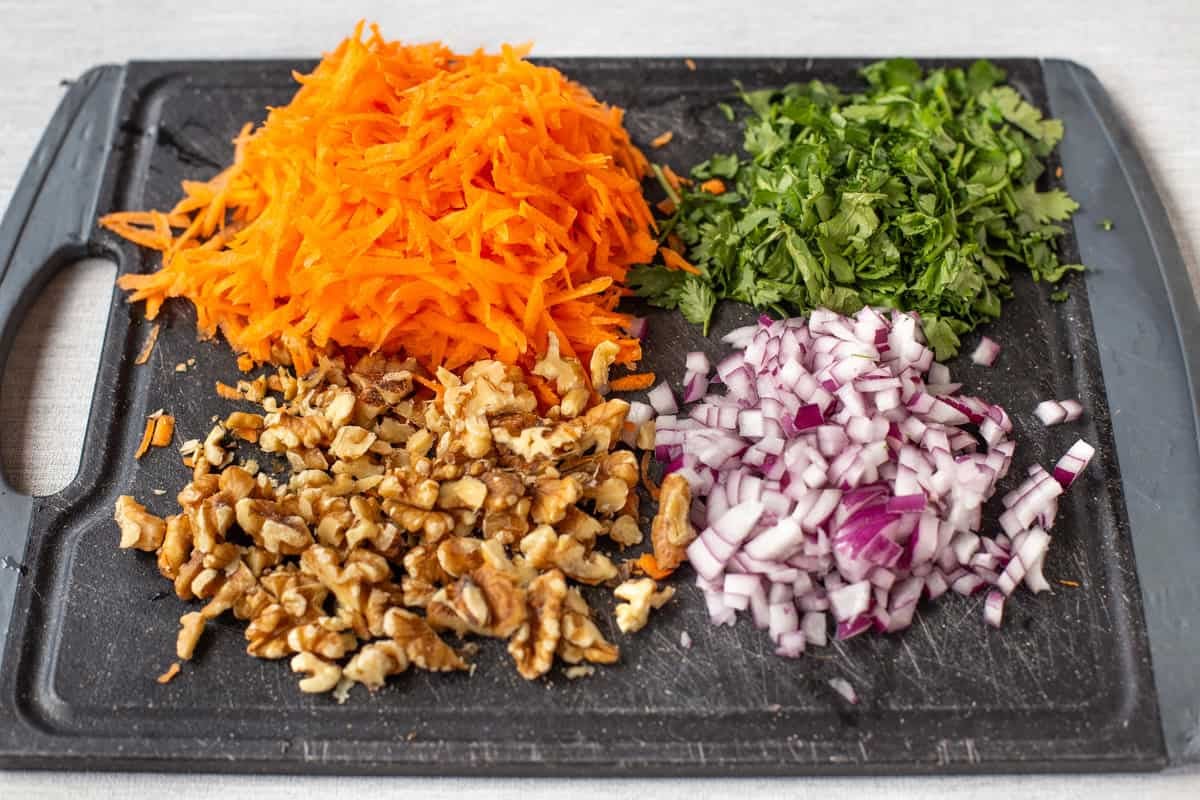 Chopped vegetables and nuts on a cutting board.