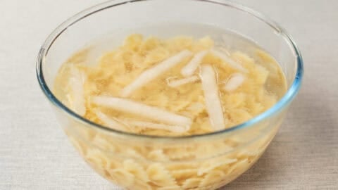 Cooked pasta cooling in a bowl of ice water.