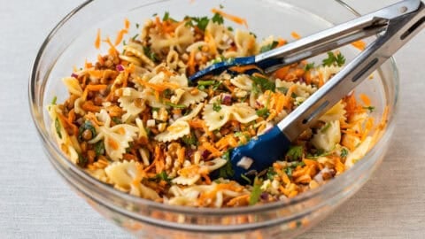 A bowl of French lentil pasta salad with a pair of tongs.