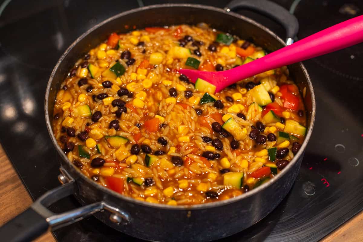 Orzo, black beans and veggies in a large frying pan.