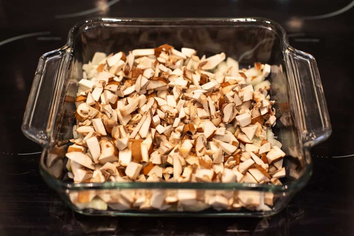 Chopped mushrooms and onion in a baking dish.