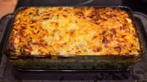 A pan of cheesy potato enchiladas with crispy topping.