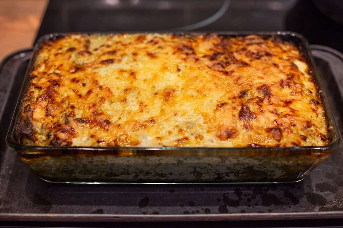 A pan of cheesy potato enchiladas with crispy topping.