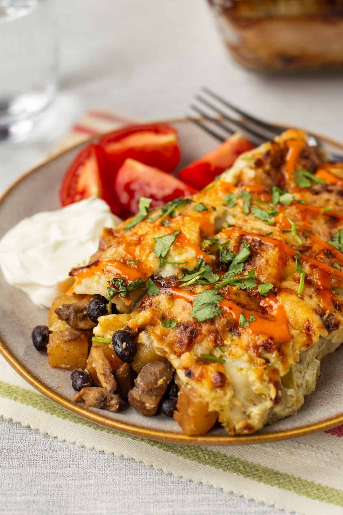 A plateful of cheesy potato enchiladas with black beans and mushrooms.