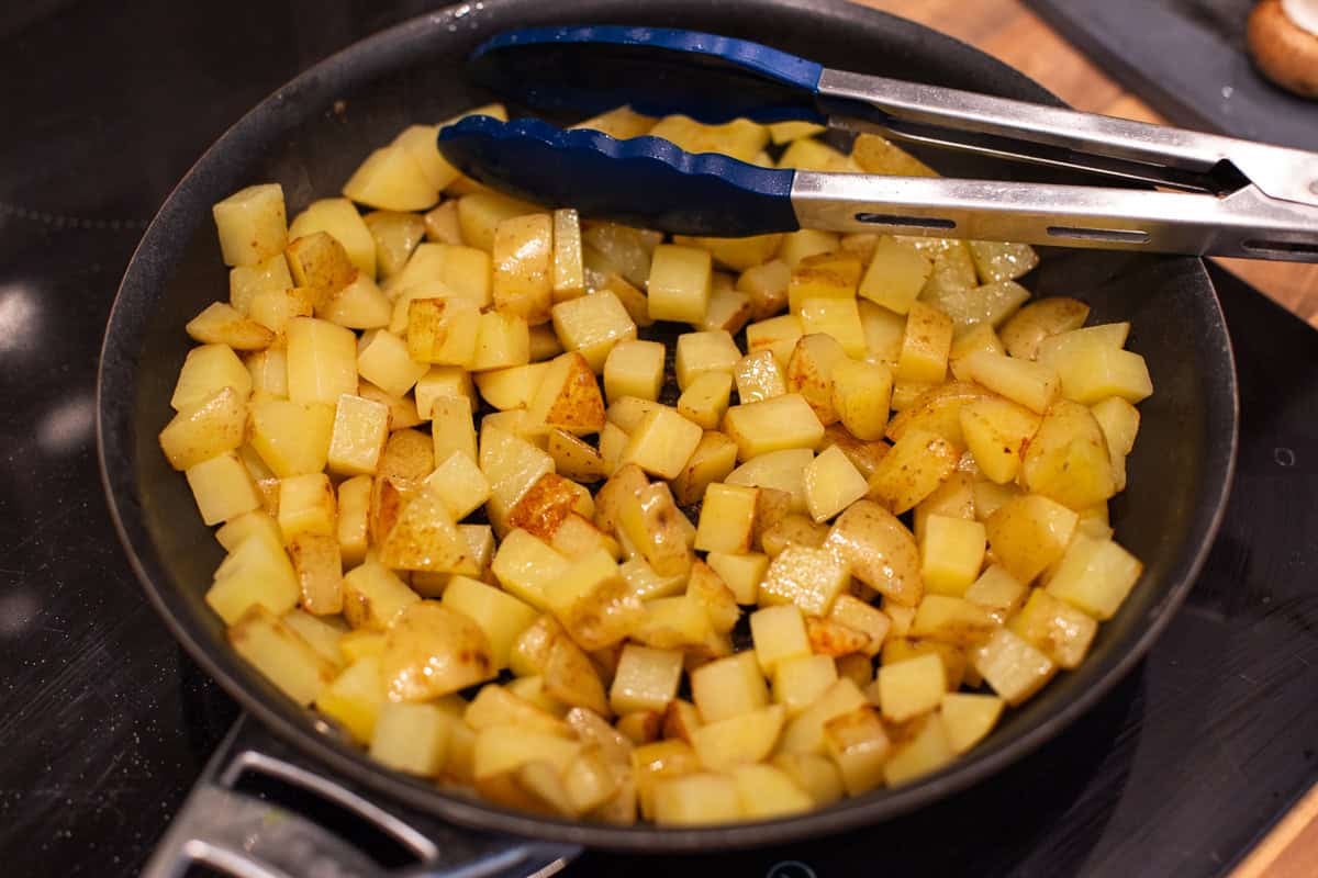 Diced potatoes cooking in a frying pan.
