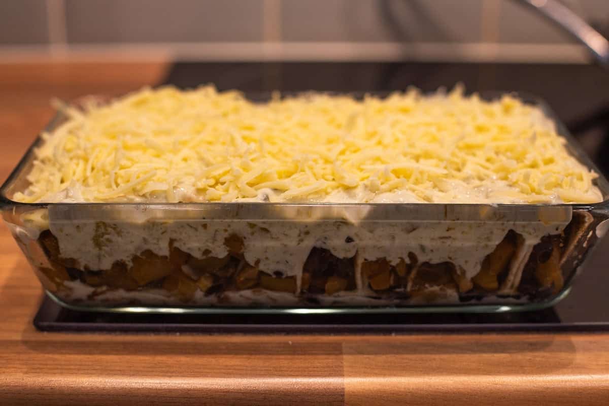 An uncooked pan of cheesy potato enchiladas.