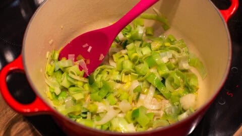 Sautéed leeks in a large pot on a stovetop.